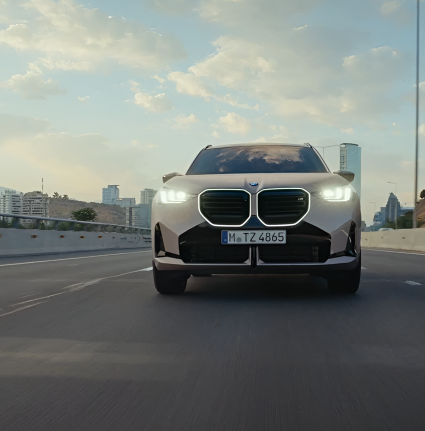 Modelo BMW X3 en calle de ciudad con edificios de fondo.