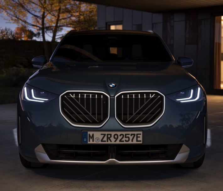 Modelo BMW X3 en calle de ciudad con edificios de fondo.