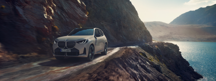 Modelo BMW X3 en calle de ciudad con edificios de fondo.