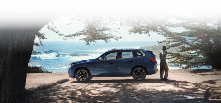 Modelo BMW X3 en calle de ciudad con edificios de fondo.